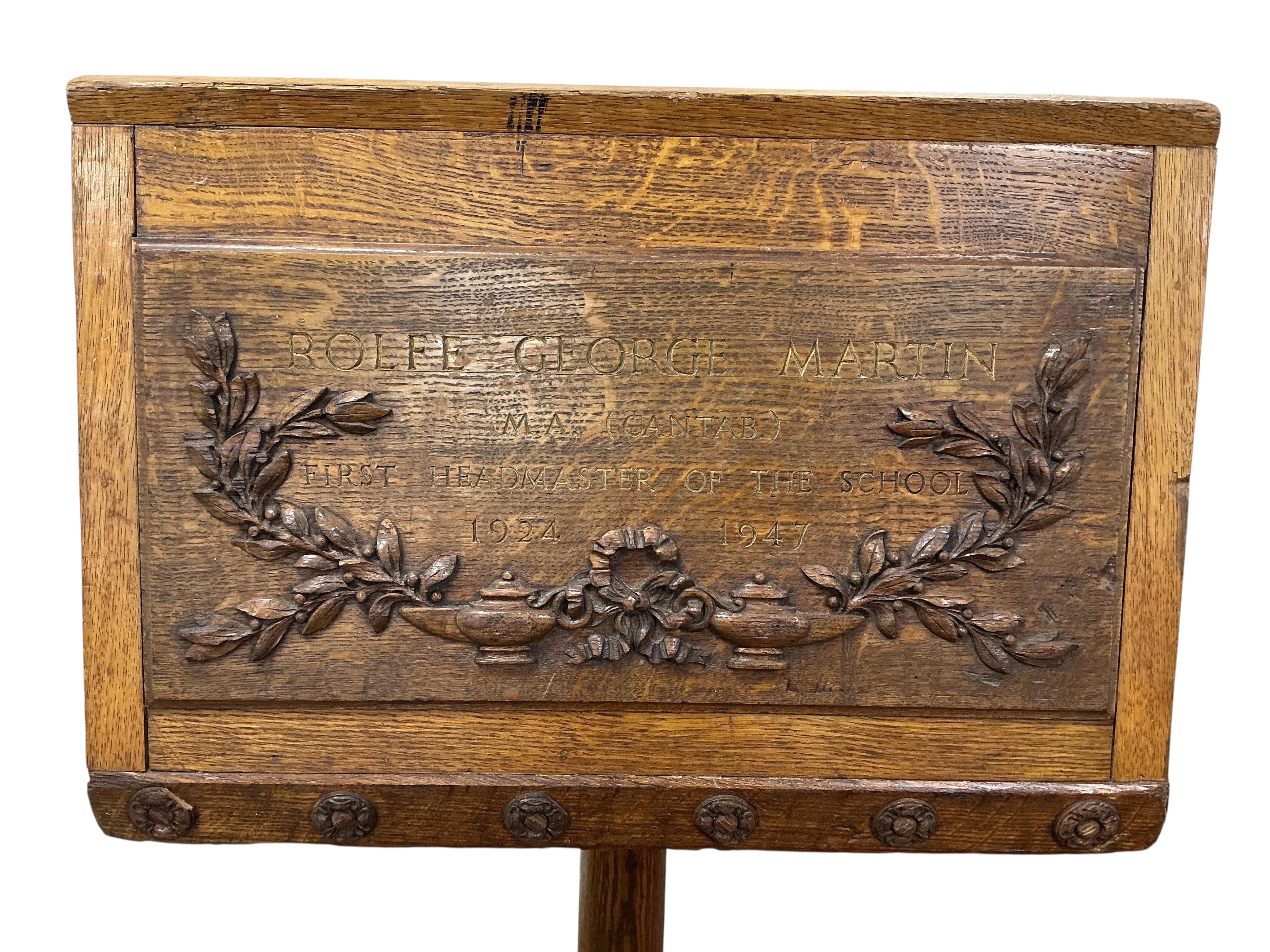 A mid 20th century oak lectern carved with ribbon fold floral swag and the legend “Rolfe George Martin, M.A (Cantab), First Headmaster of The School, 1924 - 1947. Height 142cm.